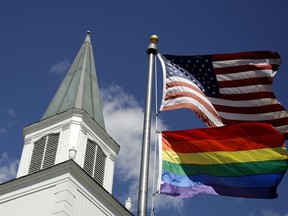 FILE - In this April 19, 2019 file photo, a gay pride rainbow flag flies along with the U.S. flag in front of the Asbury United Methodist Church in Prairie Village, Kan. On Friday, April 26, 2019, the United Methodist Church's judicial council upheld the legality of major portions of a new plan that strengthens the denomination's bans on same-sex marriage and ordination of LGBT pastors.