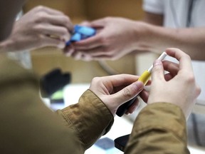 FILE - In this Oct. 22, 2018 file photo, visitors try out a pen-like "heat-not-burn" device at an IQOS store at Ginza in Tokyo. On Tuesday, April 30, 2019, the U.S. Food and Drug Administration said it will allow Philip Morris International to sell the cigarette alternative that heats tobacco without burning it.