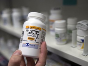 FILE - In this Friday, July 8, 2016 photo, a pharmacist holds a bottle of the antibiotic doxycycline hyclate in Sacramento, Calif. According to a study released on Monday, April 8, 2019, sniffling, coughing kids who were seen via telemedicine visits were far more likely to be prescribed antibiotics than kids who went to a doctor's office or clinic.