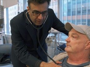 In this February 2019 photo provided by Brigham and Women's Hospital, Dr. Mandeep Mehra, executive director of Brigham's Center for Advanced Heart Disease, checks on patient James Sullivon at the hospital in Boston. Sullivon, who received a hepatitis C-positive heart transplant, was given antiviral medicine shortly after the procedure in hopes of blocking hepatitis C infection rather than having to treat it.