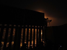 FILE - In this Dec. 2, 2018, file photo, Honduran migrants climb over a section of the U.S. border fence from Playas of Tijuana, Mexico, before handing themselves in to border control agents. A surge in family arrivals, largely from Guatemala and Honduras, has led Border Patrol agents to shift attention from preparing criminal cases to caring for children.