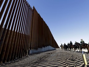 FILE - In this Oct. 26, 2018, file photo, mounted Border Patrol agents ride along a newly fortified border wall structure in Calexico, Calif. President Donald Trump is visiting Calexico on Friday, April 5, 2019, to tour the recently-built portion of the border fence that bears a silver plaque with his name on it.