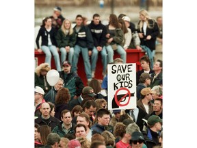 FILE - In this April 25, 1999, file photo, a participant at a memorial service for the victims of the Columbine High School shooting rampage holds a "NO GUNS" sign in Littleton, Colo. Data shows that such shootings are less frequent and with fewer killed than in the years that preceded Columbine. Still, Americans worry about how safe schools are.