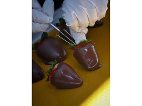 This photo shows chocolate covered strawberries at Godiva's new cafe in New York, Tuesday April 16, 2019. Godiva, the private Belgium chocolate maker, is looking beyond its iconic gold gift box of chocolates. The confectioner is rolling out 2,000 cafes that will serve a complete menu of items like the croiffle, a croissant and waffle hybrid.