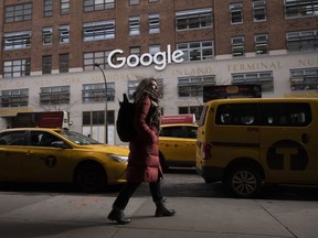 FILE- In this Dec. 17, 2018, file photo a woman walks past Google offices in New York. Alphabet Inc., parent company of Google, reports financial results on Monday, April 29, 2019.