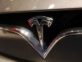 FILE- This Oct. 3, 2018, file photo shows a Tesla emblem at the Auto show in Paris. Tesla CEO Elon Musk appears poised to transform the company's electric cars into driverless vehicles in a risky bid to realize a bold vision that he has been floating for years. The technology required to make that quantum leap is scheduled to be shown off to Tesla investors Monday, April 22, 2019, at the company's Palo Alto, Calif., headquarters.