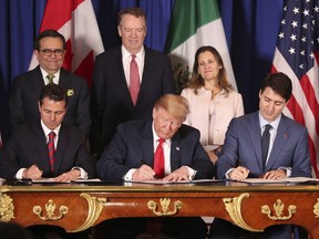 FILE - In this Nov. 30, 2018 file photo, President Donald Trump, center, sits between Canada's Prime Minister Justin Trudeau, right, and Mexico's President Enrique Pena Nieto as they sign a new United States-Mexico-Canada Agreement that is replacing the NAFTA trade deal, during a ceremony at a hotel before the start of the G20 summit in Buenos Aires, Argentina. Trump's new North America trade agreement would give the U.S. economy only a modest boost, an independent federal agency finds.