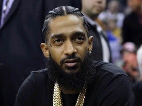 FILE - This March 29, 2018 file photo shows rapper Nipsey Hussle at an NBA basketball game between the Golden State Warriors and the Milwaukee Bucks in Oakland, Calif. Hussle was shot and killed Sunday, March 31, 2019 outside of his clothing store in Los Angeles.