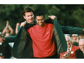 FILE - In this April 13, 1997, file photo, Masters champion Tiger Woods receives his Green Jacket from last year's winner Nick Faldo, rear, at the Augusta National Golf Club in Augusta, Ga. Woods completes an amazing journey by winning the 2019 Masters, overcoming 11 years of personal foibles and professional pain that seemed likely to be his lasting legacy.