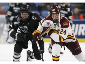 Minnesota Duluth defenseman Mikey Anderson (24) and Providence forward Jack Dugan (12) skate during the first period in the semifinal of the Frozen Four NCAA college hockey tournament, Thursday, April 11, 2019, in Buffalo, N.Y.