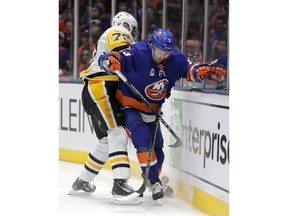 Pittsburgh Penguins right wing Patric Hornqvist (72), of Sweden, and New York Islanders defenseman Adam Pelech (3) compete for possession during the first period of Game 2 of an NHL hockey first-round playoff series Friday, April 12, 2019, in Uniondale, N.Y.