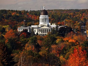 FILE - In this Oct. 23, 2017, file photo, the State House is surrounded by fall foliage in Augusta, Maine. At least 14 Democrats and eight Republican lawmakers in Maine have gone on to register as paid lobbyists in the past three decades, a practice that is being targeted by a bill advancing in the Legislature. The Maine House and Senate last week advanced a bill to ban future lawmakers from any paid lobbying within their first year out of office. The state ethics commissions had called for the change in 2017.
