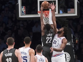 Brooklyn Nets guard Caris LeVert (22) dunks past Philadelphia 76ers center Joel Embiid (21) during the first half of Game 4 of a first-round NBA basketball playoff series, Saturday, April 20, 2019, in New York.