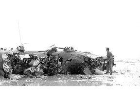 FILE - In this 1944 photo provided by the U.S. Army, a member of the military stands near a B-24 bomber that crashed shortly after takeoff from an airfield on the Tarawa atoll in the Gilbert Islands in the Pacific Ocean during World War II. A relative of New York Airman Vincent J. Rogers Jr., whose remains were recently identified more than 75 years after he died in World War II, says his reburial will likely be in a rural upstate cemetery. (U.S. Army via AP, File)