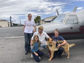 In this photo provided by the Humane Society of Broward County, kneeling from left to right, Chloe, Doug and Chase Peterson greet their long-lost German Shepherd dog Cedar on Saturday, April 20, 2019, at Fort Lauderdale Executive Airport, in Fort Lauderdale, Fla. Cedar, 2, was stolen from her home in Southwest Ranches in 2017 and located this month in Colorado. Standing is pilot Ted DuPuis.