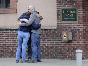 People embrace in front of a funeral home preparing to receive the remains of Staff Sgt. Christopher Slutman in the Bronx borough of New York, Monday, April 22, 2019. Firefighters in three states are honoring the U.S. Marine and New York City firefighter who was killed by a roadside bomb in Afghanistan.