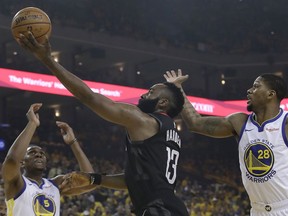 Houston Rockets guard James Harden (13) shoots between Golden State Warriors center Kevon Looney (5) and forward Alfonzo McKinnie (28) during the first half of Game 1 of a second-round NBA basketball playoff series in Oakland, Calif., Sunday, April 28, 2019.