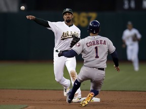 Oakland Athletics' Marcus Semien, left, throws over Houston Astros' Carlos Correa (1) to complete a double play on Josh Reddick during the second inning of a baseball game Wednesday, April 17, 2019, in Oakland, Calif.