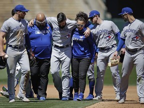 Toronto Blue Jays pitcher Matt Shoemaker, third from left, is helped off the field after sustaining an injury on a rundown play against the Oakland Athletics in the third inning of a baseball game Saturday, April 20, 2019, in Oakland, Calif.