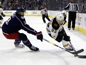 Columbus Blue Jackets defenseman Seth Jones, left, works against Boston Bruins forward Karson Kuhlman during the first period of an NHL hockey game in Columbus, Ohio, Tuesday, April 2, 2019.