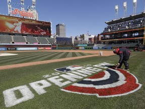 Mathew Gudin paints the opening day signage on the field before the Cleveland Indians play the Chicago White Sox in a baseball game, Monday, April 1, 2019, in Cleveland.