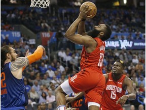 Houston Rockets guard James Harden (13) goes up for a shot between Oklahoma City Thunder center Steven Adams, left, and Rockets' Clint Capela (15) during the first half of an NBA basketball game Tuesday, April 9, 2019, in Oklahoma City.
