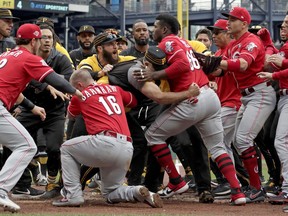 Cincinnati Reds' Yasiel Puig (66) is restrained by Pittsburgh Pirates bench coach Tom Prince, in the middle of a bench clearing brawl during the fourth inning of a baseball game in Pittsburgh, Sunday, April 7, 2019.