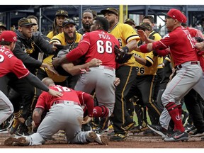 Cincinnati Reds' Yasiel Puig (66) is restrained by Pittsburgh Pirates bench coach Tom Prince, in the middle of a bench clearing brawl during the fourth inning of a baseball game in Pittsburgh, Sunday, April 7, 2019.