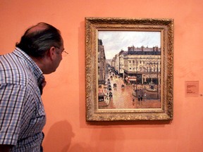 This May 12, 2005 file photo shows an unidentified visitor viewing the Impressionist painting called "Rue St.-Honore, Apres-Midi, Effet de Pluie" painted in 1897 by Camille Pissarro, on display in the Thyssen-Bornemisza Museum in Madrid.