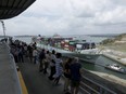 In this April 20, 2019 photo, tourists watch as a cargo ship transits through the Agua Clara locks of the Panama Canal.