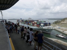 In this April 20, 2019 photo, tourists watch as a cargo ship transits through the Agua Clara locks of the Panama Canal.