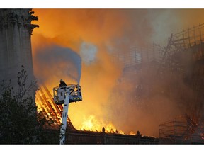 A fire fighter uses a hose as Notre Dame cathedral is burning in Paris, Monday, April 15, 2019. A catastrophic fire engulfed the upper reaches of Paris' soaring Notre Dame Cathedral as it was undergoing renovations Monday, threatening one of the greatest architectural treasures of the Western world as tourists and Parisians looked on aghast from the streets below.