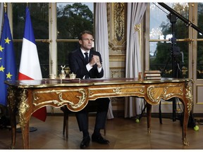 French President Emmanuel Macron sits at his desk after addressing the French nation following a massive fire at Notre Dame Cathedral, at Elysee Palace in Paris, Tuesday, April 16 2019. Macron said he wants to see the fire-ravaged Notre Dame cathedral to be rebuilt within five years.
