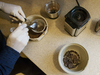 A midwife uses a sieve while grinding dehydrated human placenta.