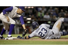 San Diego Padres shortstop Fernando Tatis Jr. dives under the tag by Arizona Diamondbacks first baseman Wilmer Flores, left, to get back to first base safely during the eighth inning of a baseball game Thursday, April 11, 2019, in Phoenix. The Padres won 7-6.