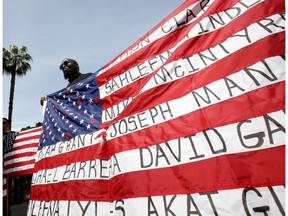 Malaki Seku Amen holds up an American flag with the names of people shot and killed by law enforcement officers, as he joins other in support of a bill that would restrict the use of deadly force by police, Monday, April 8, 2019, in Sacramento, Calif. The bill, AB392 by Democratic Assembly members Shirley Weber, of San Diego, and Kevin McCarty, of Sacramento, would require officers to use de-escalation tactics and allow them to use deadly force only when it is necessary to prevent immediate harm to themselves or others.