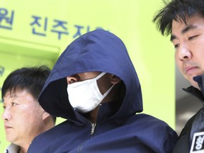 A 42-year-old man, center, identified only by his family name Ahn, is escorted by police officers at a district court in Jinju, South Korea, Thursday, April 18, 2019. South Korean police are investigating Ahn accused of setting his apartment on fire and stabbing neighbors trying to flee, killing five people and injuring 13 others.