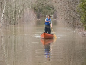 Jarred Lawson paddles a canoe down Bourque Lane which is flooded by the water of the St. John River in Fredericton on Sunday, April 21, 2019.
