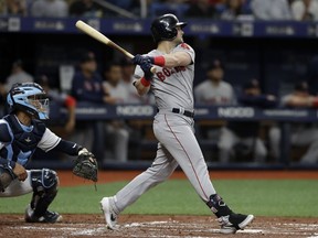 Boston Red Sox's Andrew Benintendi follows the flight of his grand slam off Tampa Bay Rays starting pitcher Charlie Morton during the second inning of a baseball game Saturday, April 20, 2019, in St. Petersburg, Fla. Catching for the Rays is Michael Perez.