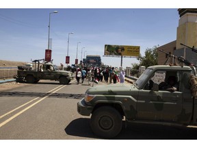 Demonstrators walk past army vehicles protecting the entrance to a rally near the military headquarters in Khartoum, Sudan, Monday, April 15, 2019. The Sudanese protest movement on Monday welcomed the "positive steps" taken by the ruling military council, which held talks over the weekend with the opposition leaders and released some political prisoners. The praise came despite a brief incident earlier Monday where activists said soldiers attempted to disperse the ongoing protest sit-in outside the military headquarters in the capital, Khartoum, but eventually backed off.