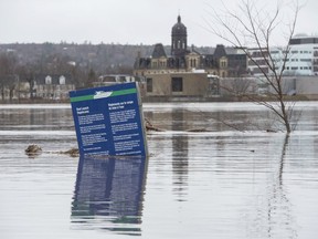 The New Brunswick Legislature is seen behind a boat ramp sign in Carleton Park surrounded by the flood water and debris from the St. John River in Fredericton, N.B.