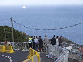 Police officers stand on the curve in the road where a bus went over the edge and crashed into a house below in Canico, on Portugal's Madeira Island, Thursday April 18, 2019. All the 29 people killed in a bus crash on Portugal's Madeira Island were German, Portugal's foreign ministry confirmed Thursday. The bus carrying 55 people, all but two of them German tourists, rolled down a steep hill after veering off the road on a bend east of Madeira's capital, Funchal, on Wednesday evening when it was still light and in fine weather. The crash injured 28 others.