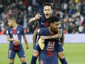 PSG's Neymar, top, sits on the back of PSG's Presnel Kimpembe after the French League One soccer match between Paris-Saint-Germain and Monaco at the Parc des Princes stadium in Paris, Sunday April 21, 2019. PSG were celebrating winning the French League one title.