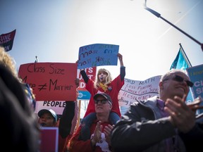 Camryn Bloom, 6, sits on the shoulders of family friend Paul Pellerin at Queen's Park to protest the provincial government's recently announced changes to education during the Rally for Education in Toronto.