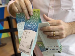 FILE - In this June 20, 2016, file photo, a man handles the Olympic tickets he just purchased at a shopping mall in Rio de Janeiro, Brazil. Tokyo Olympic organizers launched their ticket website on Thursday, April 18, 2019, which is where only Japan residents can buy tickets when they go on sale on May 9. The site can also be accessed by people outside Japan, where basic prices are listed. But they can't buy there.