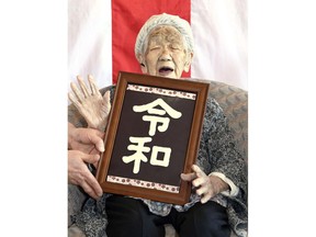 In this Monday, April 1, 2019, photo, Kane Tanaka, who is honored as the world's oldest living person by Guinness World Records at 116, poses with new era name "Reiwa," made of chocolate at a nursing home in Fukuoka, southwestern Japan. Tanaka was born in Meiji era, and will soon experience the fifth era, starting on May 1.