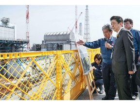 Japanese Prime Minister Shinzo Abe, foreground, visits Fukushima Dai-ichi nuclear power plant in Okuma, Fukushima prefecture, Japan, Sunday, April 14, 2019, to inspect the reconstruction effort following the tsunami, quake and nuclear accident in 2011.