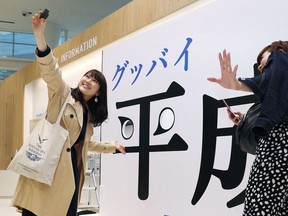 Visitors take a selfie with a panel with "Good-bye Heisei" written in Japanese at Fukuoka Tower in Fukuoka, southwestern Japan, Tuesday, April 30, 2019. Japan's Emperor Akihito is set to abdicate later in the day as Japan embraces the end of his reign with an emotion mixed with reminiscence and hopes for a new era.