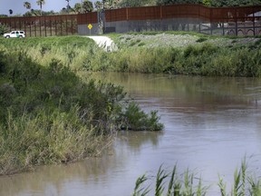FILE - In this June 26, 2018, file photo, a U.S. Border Patrol vehicle sits above the Rio Grande River at the U.S. - Mexico border in Brownsville, Texas. U.S. Border Patrol agents found a 3-year-old boy alone in a field after likely being abandoned by smugglers at the southern border, authorities said. U.S. Customs and Border Protection said late Tuesday, April 23, 2019, that the boy's name and phone numbers were written on his shoes when agents found him that morning. The agency said it is trying to reach the boy's family.