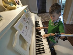 Braden Scott uses a device to support his left arm as he practices on the piano in Tomball, Texas on Friday, March 29, 2019. Braden was diagnosed with the syndrome called acute flaccid myelitis, or AFM, in 2016 and was paralyzed almost completely. The rare but mysterious illness seems to ebb and flow every other year and is beginning to alarm public health officials.